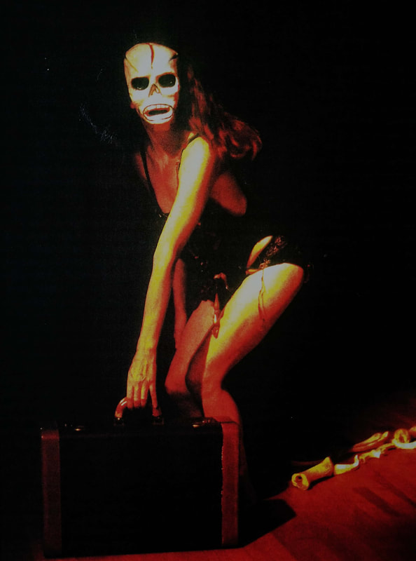 Aimee Greenberg standing with a skeleton mask holding a suitcase in Dark Moon of Lilith